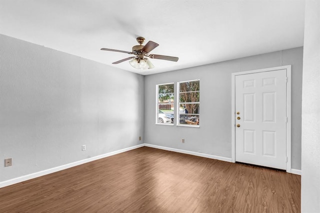 spare room with ceiling fan, baseboards, and dark wood finished floors