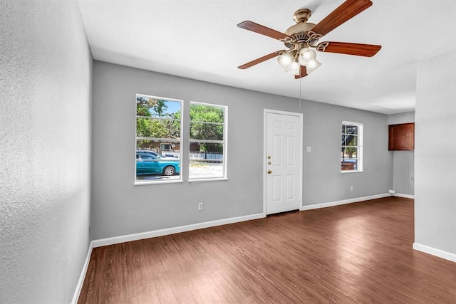 empty room featuring dark wood-style floors, a healthy amount of sunlight, and baseboards