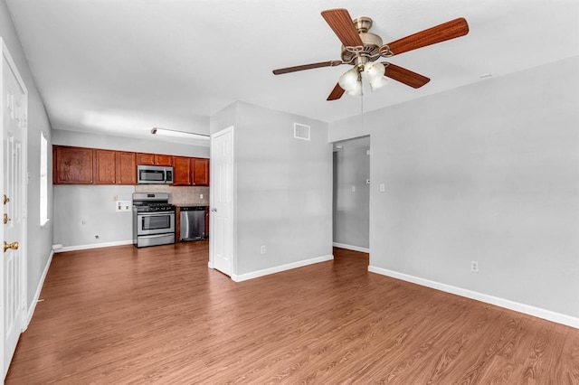 unfurnished living room featuring wood finished floors, visible vents, and baseboards