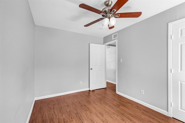 unfurnished bedroom featuring ceiling fan, wood finished floors, visible vents, and baseboards