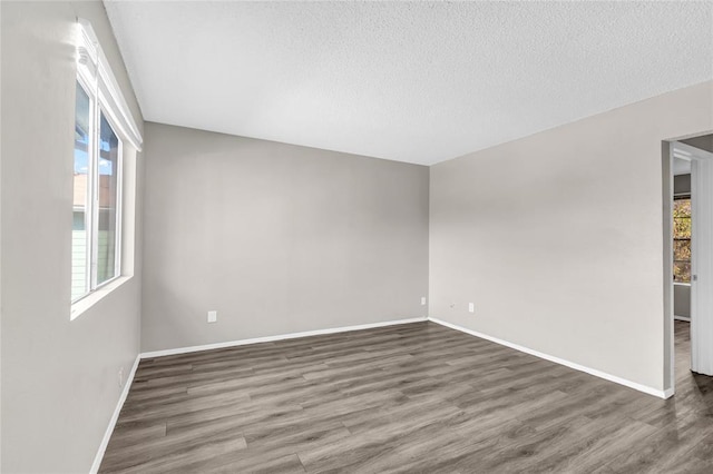 empty room featuring a textured ceiling, baseboards, and wood finished floors