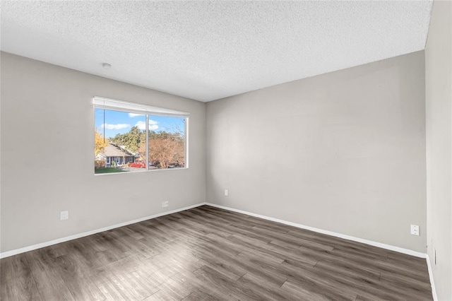 spare room featuring a textured ceiling, baseboards, and dark wood-type flooring