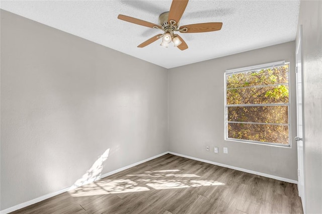 empty room with a textured ceiling, baseboards, and wood finished floors