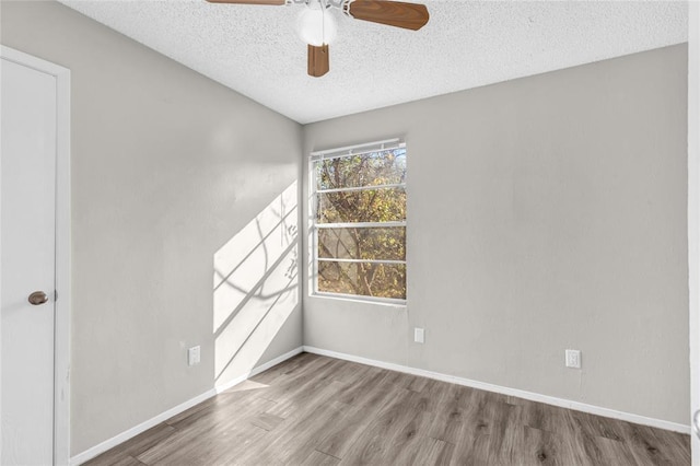 empty room featuring a textured ceiling, wood finished floors, a ceiling fan, and baseboards