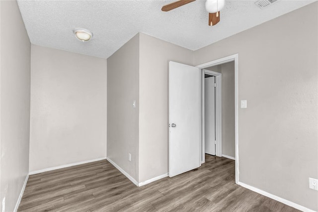 unfurnished bedroom with ceiling fan, a textured ceiling, baseboards, and wood finished floors