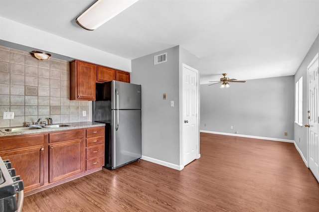 kitchen featuring wood finished floors, visible vents, a sink, freestanding refrigerator, and tasteful backsplash