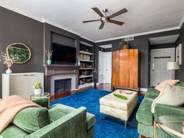 living room with a fireplace, visible vents, ornamental molding, a textured ceiling, and wood finished floors