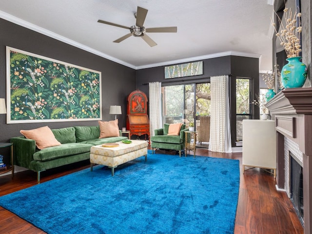 living room featuring ornamental molding, a fireplace, wood finished floors, and a ceiling fan