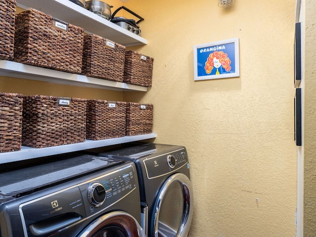 laundry room featuring laundry area, a textured wall, and washing machine and clothes dryer