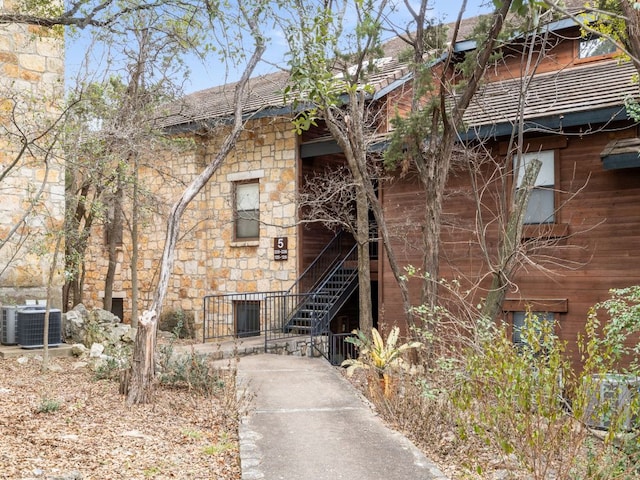 view of building exterior featuring stairway and central AC unit