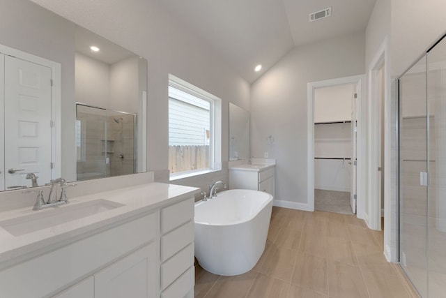 9908 Ephemeral Dr, Manor, TX 78653 - full bathroom with a stall shower, two vanities, a freestanding bath, a spacious closet, and lofted ceiling