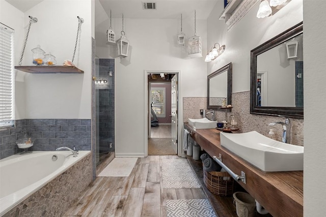 22128 Rose Grass Ln, Spicewood, TX 78669 - bathroom featuring a shower stall, a bath, double vanity, wood finished floors, and tile walls