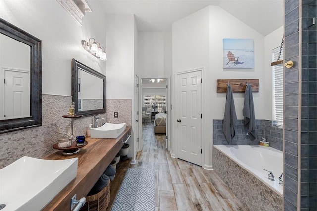 22128 Rose Grass Ln, Spicewood, TX 78669 - bathroom featuring connected bathroom, a garden tub, double vanity, wood finished floors, and high vaulted ceiling