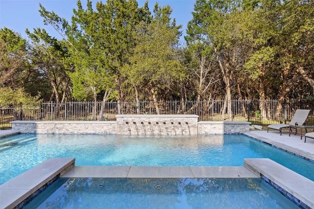 view of pool with a pool with connected hot tub and fence