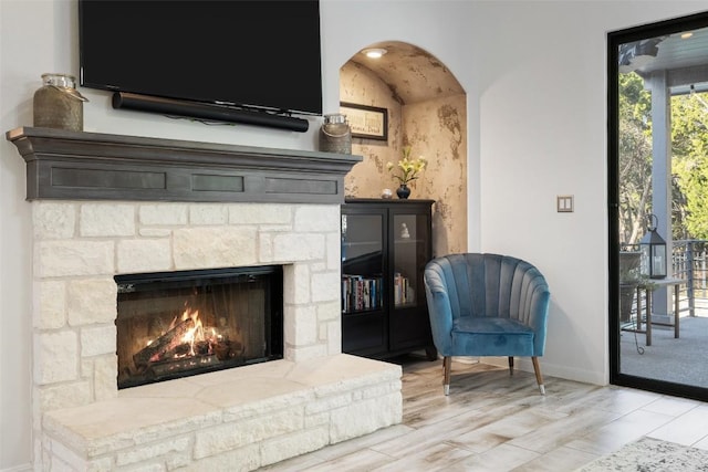 22128 Rose Grass Ln, Spicewood, TX 78669 - sitting room with baseboards, a fireplace, wood finished floors, and arched walkways