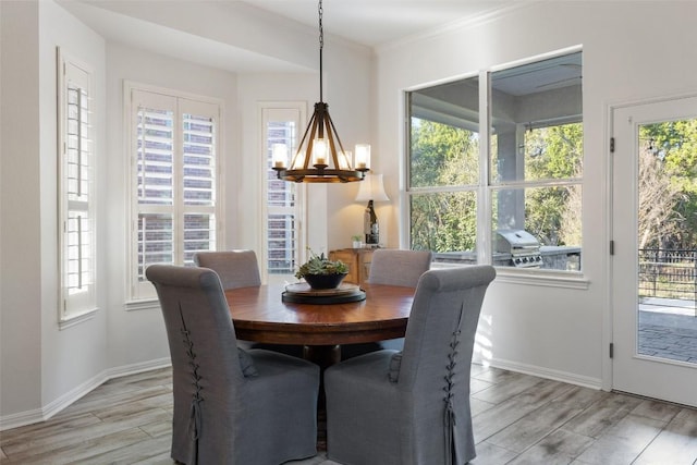 dining space featuring baseboards, ornamental molding, a notable chandelier, and wood finish floors