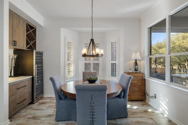 dining room with a wealth of natural light, baseboards, light wood finished floors, and a notable chandelier