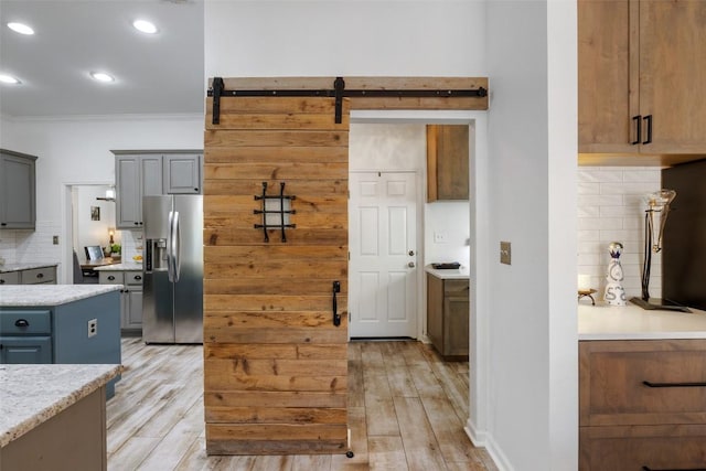 kitchen with decorative backsplash, stainless steel fridge, light wood finished floors, and gray cabinetry