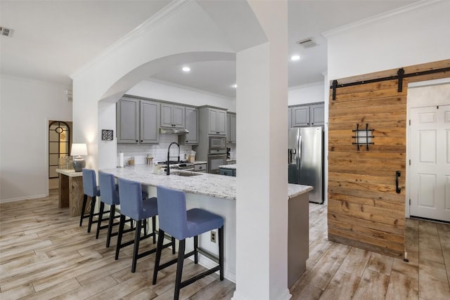 kitchen featuring gray cabinetry, light wood-style floors, a sink, stainless steel fridge, and oven