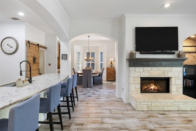 22128 Rose Grass Ln, Spicewood, TX 78669 - living area with light wood-type flooring, ornamental molding, a stone fireplace, a chandelier, and recessed lighting