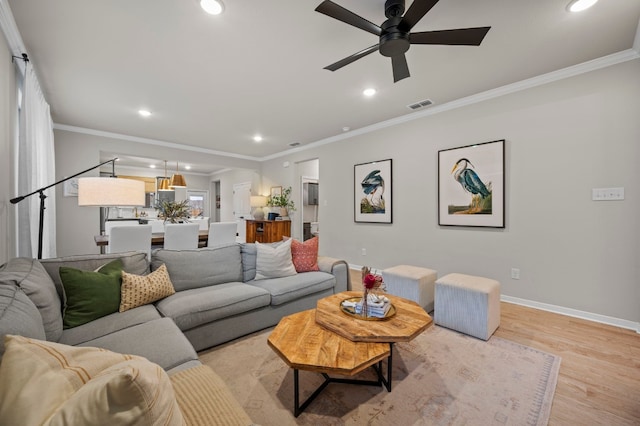 living room with light wood finished floors, baseboards, visible vents, ornamental molding, and recessed lighting