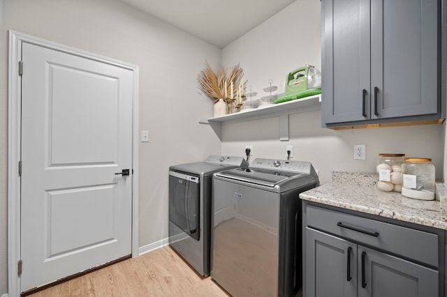 laundry room featuring cabinet space, independent washer and dryer, light wood-style flooring, and baseboards