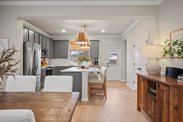 kitchen featuring light wood-style flooring, ornamental molding, a center island, stainless steel appliances, and gray cabinetry