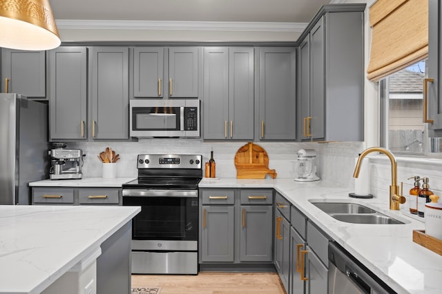 kitchen featuring crown molding, stainless steel appliances, tasteful backsplash, light wood-style flooring, and a sink