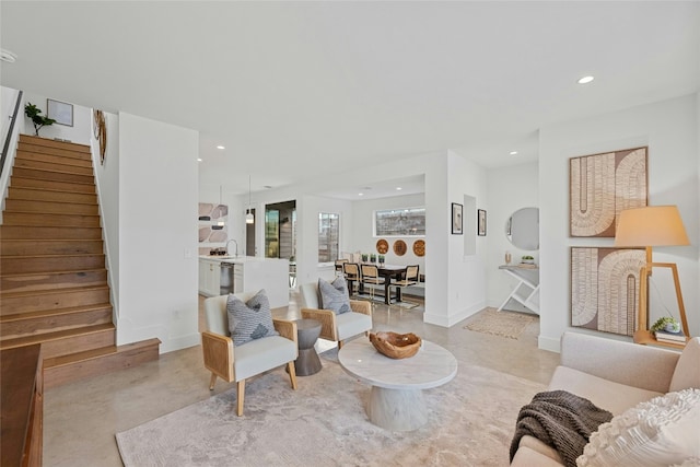 living area with stairway, recessed lighting, baseboards, and concrete flooring