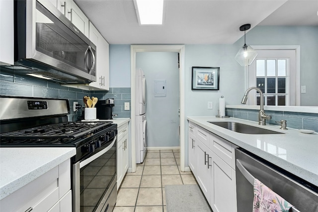 kitchen featuring light tile patterned flooring, a sink, white cabinets, appliances with stainless steel finishes, and backsplash