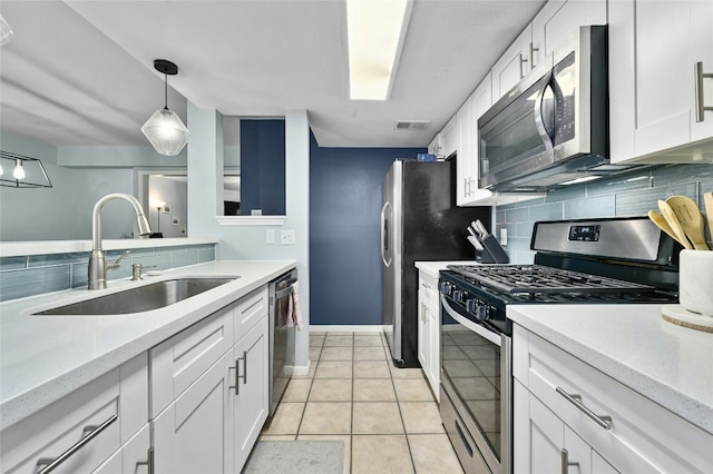 kitchen featuring a sink, backsplash, stainless steel appliances, white cabinets, and light tile patterned floors