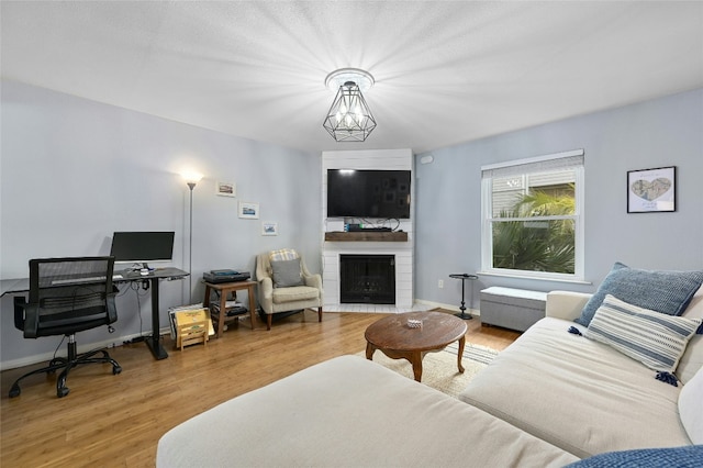 living area with baseboards, a large fireplace, and wood finished floors