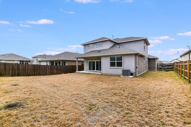 rear view of property featuring stucco siding, central air condition unit, a lawn, a patio area, and a fenced backyard