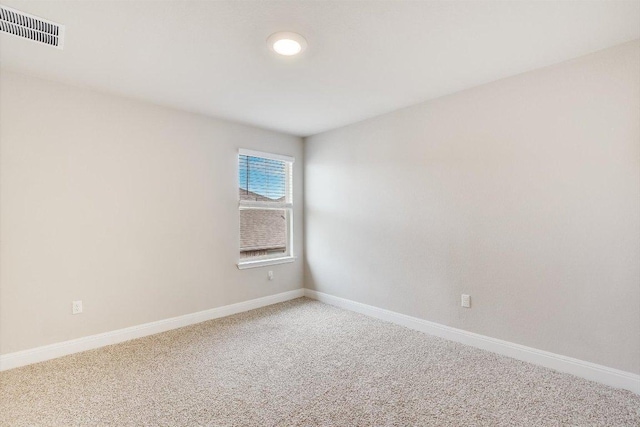 spare room featuring light carpet, visible vents, and baseboards