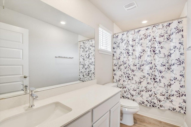 full bathroom with visible vents, toilet, wood finished floors, shower / bath combo with shower curtain, and vanity