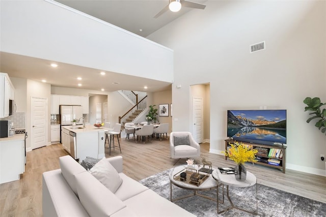 living room with light wood-style floors, recessed lighting, visible vents, and stairs