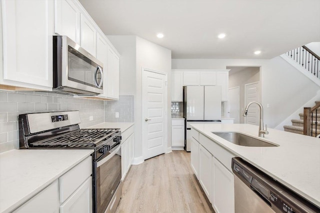 kitchen with light wood-style flooring, recessed lighting, stainless steel appliances, a sink, and white cabinetry