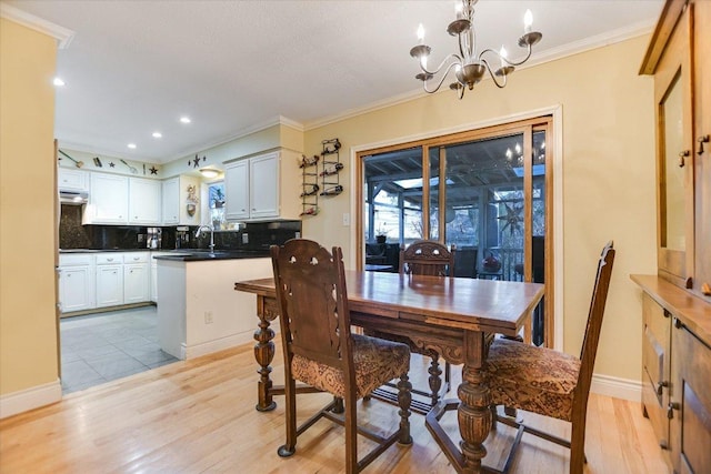 dining room with light wood-style floors, baseboards, crown molding, and an inviting chandelier