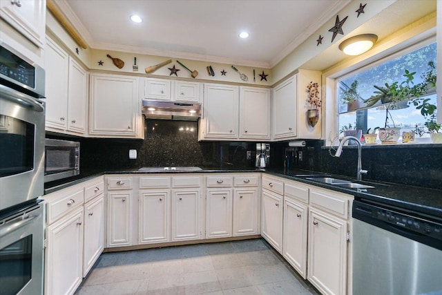 kitchen with under cabinet range hood, a sink, appliances with stainless steel finishes, backsplash, and crown molding