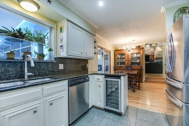 kitchen featuring beverage cooler, stainless steel appliances, a peninsula, a sink, and crown molding