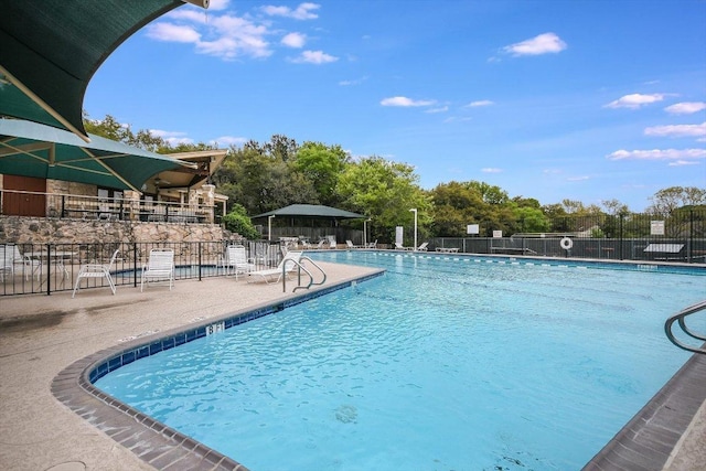 pool with a patio area and fence