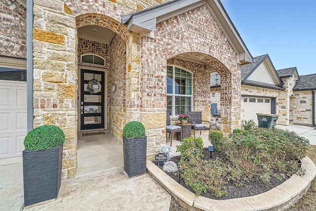 doorway to property featuring covered porch, stone siding, brick siding, and an attached garage