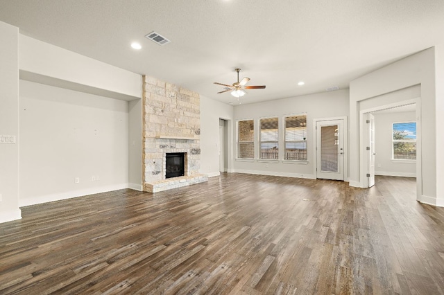 unfurnished living room with dark wood finished floors, a fireplace, visible vents, a ceiling fan, and baseboards