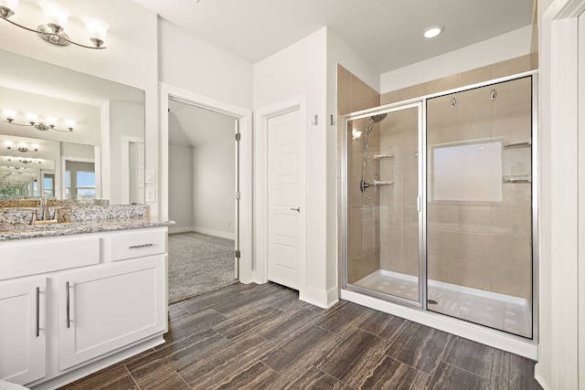 bathroom with baseboards, a shower stall, vanity, and wood tiled floor