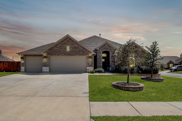 french country home with a garage, driveway, brick siding, and a front yard