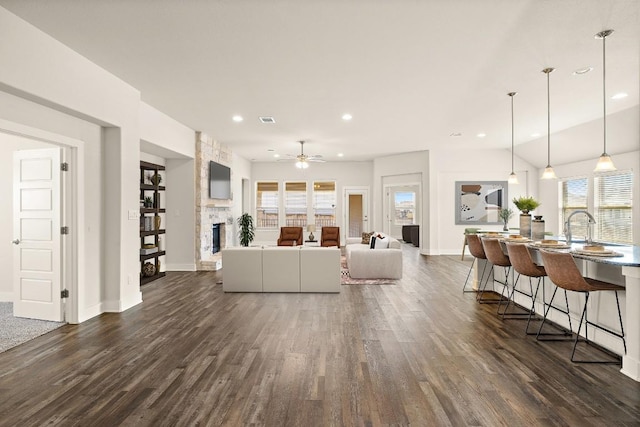 living room featuring recessed lighting, baseboards, dark wood-style flooring, and a stone fireplace