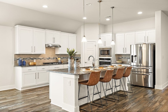 kitchen with under cabinet range hood, a sink, visible vents, appliances with stainless steel finishes, and dark wood-style floors