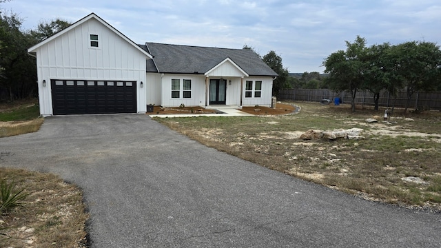 modern inspired farmhouse with driveway, a shingled roof, fence, and board and batten siding