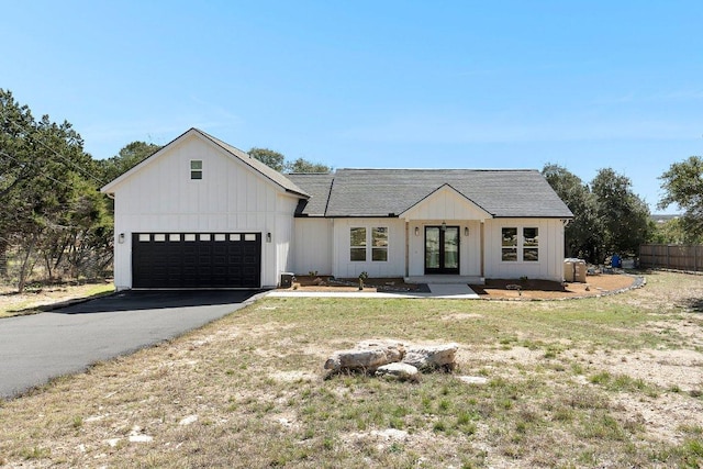 modern inspired farmhouse with a garage, french doors, driveway, and board and batten siding