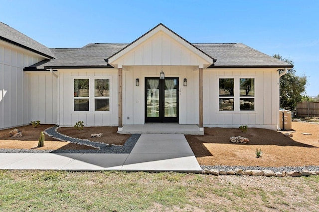 entrance to property with a shingled roof, board and batten siding, and french doors